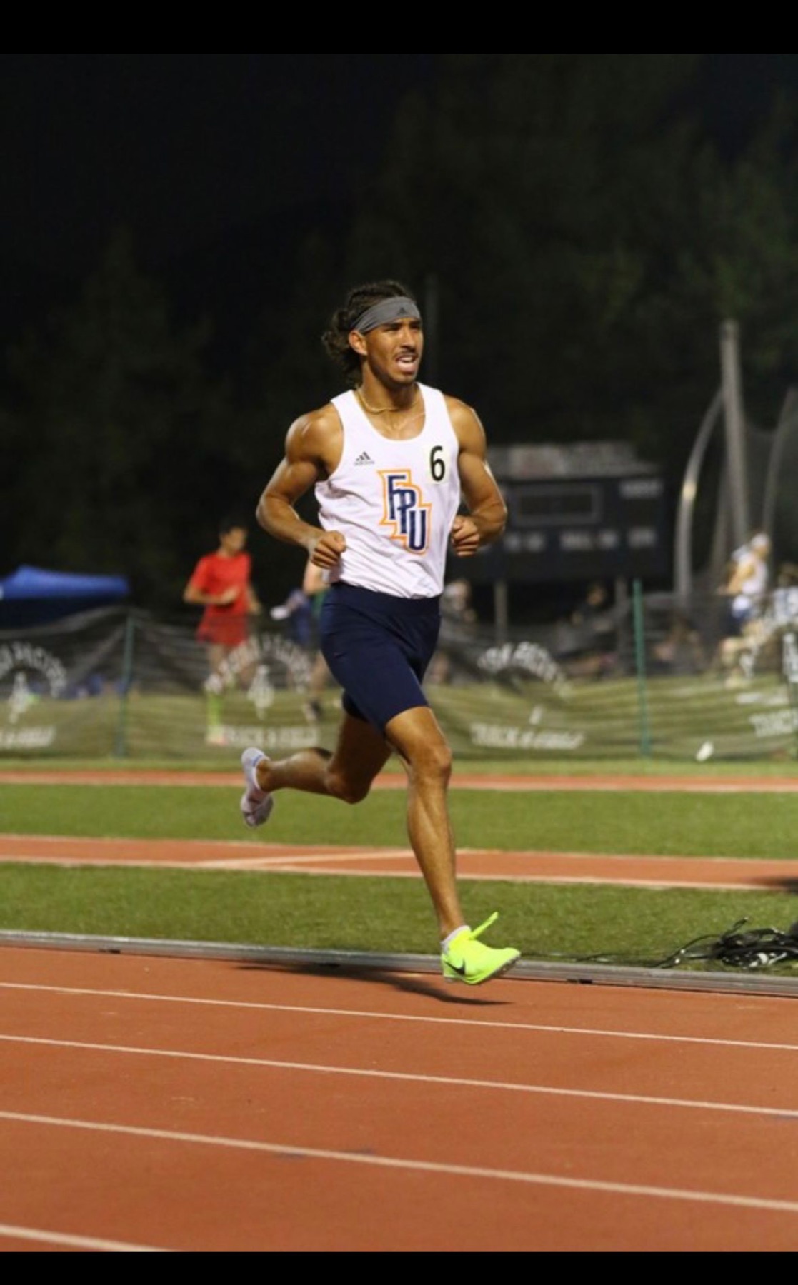 Jacob Resendez racing for Fresno Pacific at a night track meet