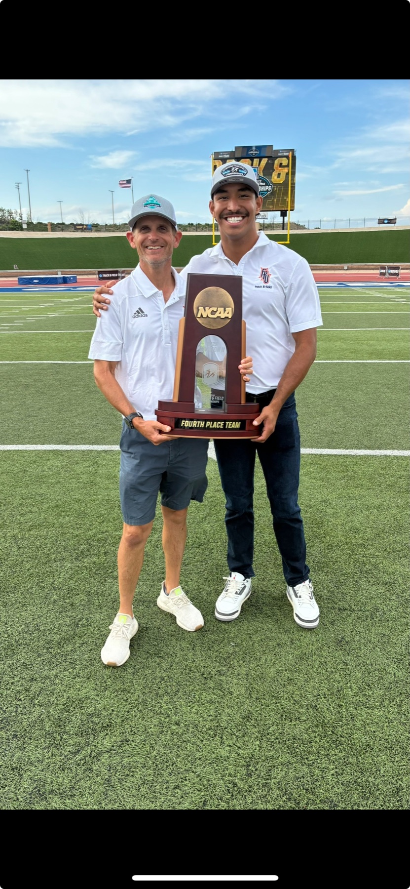 Jacob Resendez and a coach holding Fresno Pacific's NCAA fourth place team trophy